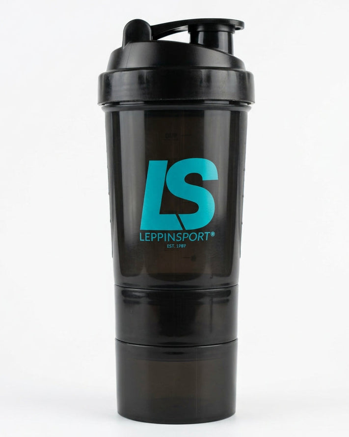 A close-up lifestyle shot of a person holding a black shaker bottle with a teal 'LS' logo on a red running track. The person is wearing white athletic socks with a matching teal and blue 'LS' logo.